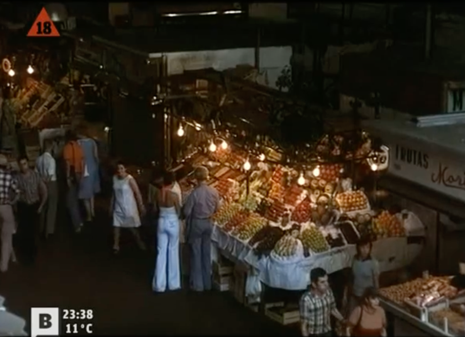 Photogramme tiré du film Tatuaje. C'est une vue en plongée d'un marché, on voit un couple devant un stand de fruit.