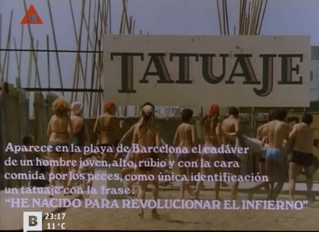 On voit des gens en tenues de plage devant une affiche géante sur laquelle figure le titre « Tatuaje », accompagnée d'une phrase descriptive qui s'affiche à l'écran : « Aparece en la playa de Barcelona el cadáver de un hombre joven, alto, rubio y con la cara comida por los peces, como única identificatión un tatuaje con la frase : "He nacido para revolucionar el infierno" »