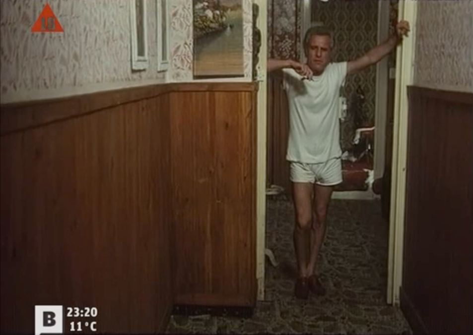 Photogramme tiré du film Tatuaje.
Un homme est dans l’embrasure d'une porte, il est en t-shirt et en short.