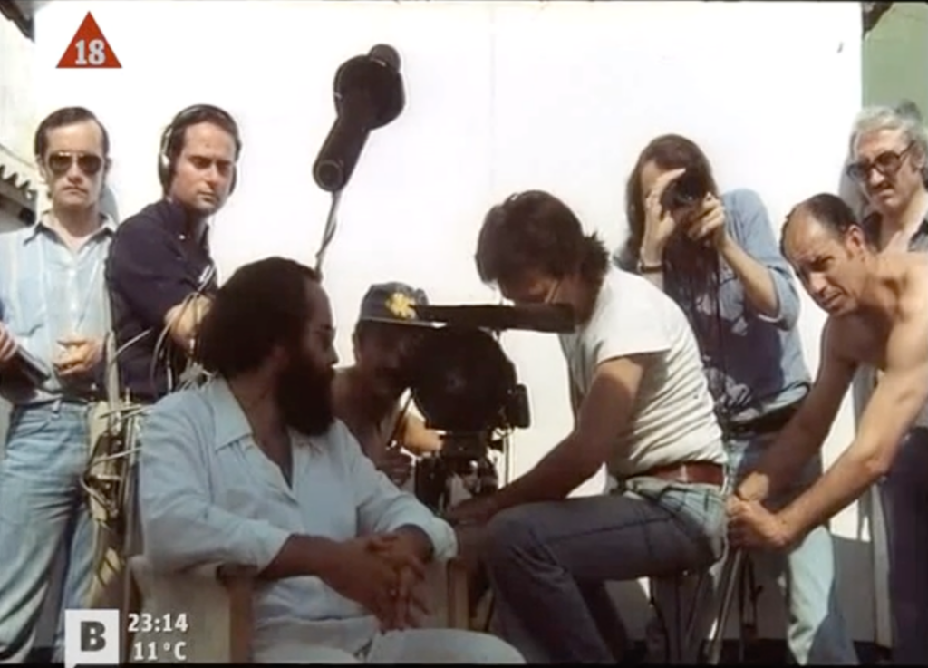 Photogramme tiré du film Tatuaje.
On voit apparaître dans le champ les membres de l'équipe technique du film eux-mêmes, autour du cinéaste.